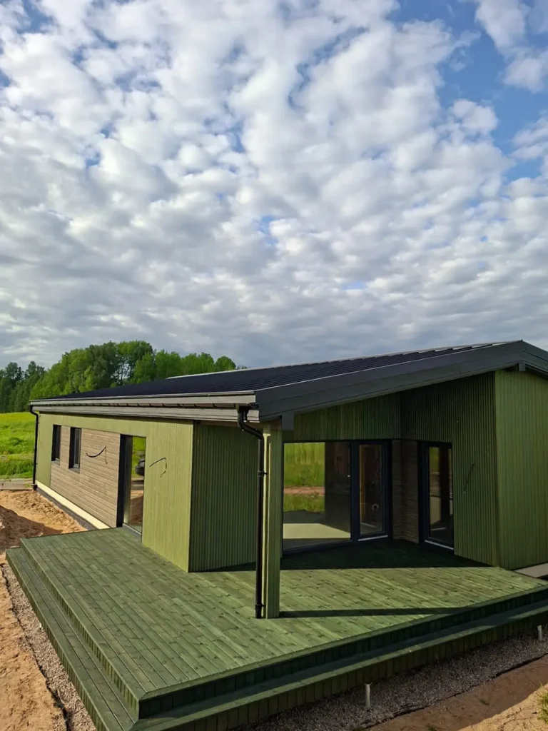 A modern single-story house with a spacious terrace in Medeksa Moss, set against a backdrop of lush greenery.