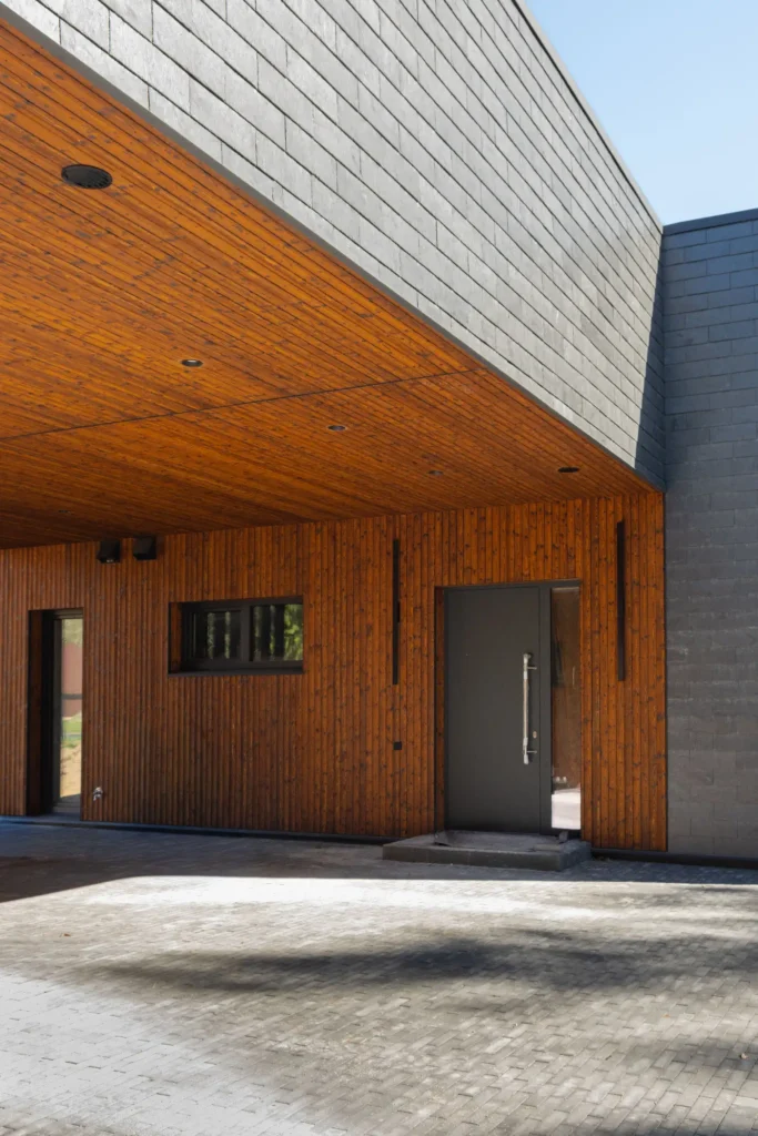 The entrance to a modern house featuring vertical charred wood siding and a gray slate facade