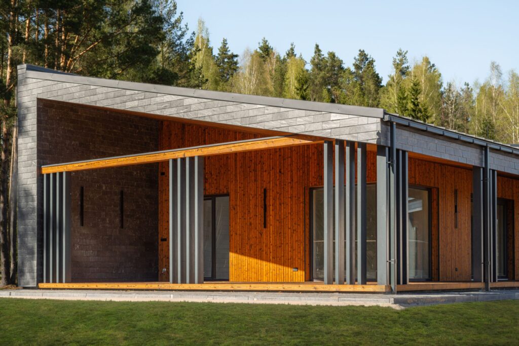 A modern single-story house with a charred wood facade, an open charred wood terrace, and metal columns